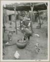 Makiena pouring milk from a calabash into a bowl (print is a cropped image)