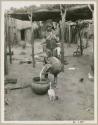 Makiena pouring milk from a calabash into a bowl (print is a cropped image)