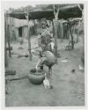 Makiena pouring milk from a calabash into a bowl (print is a cropped image)