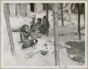 Rungiero's sister beside a cooking fire and unidentified men in the background (print is a cropped image)