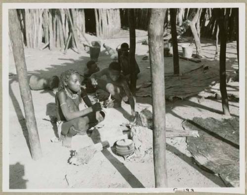 Rungiero's sister beside a cooking fire and unidentified men in the background (print is a cropped image)