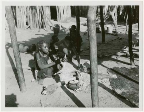 Rungiero's sister beside a cooking fire and unidentified men in the background (print is a cropped image)