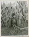 Two children seen against the big poles of the outside fence (print is a cropped image)