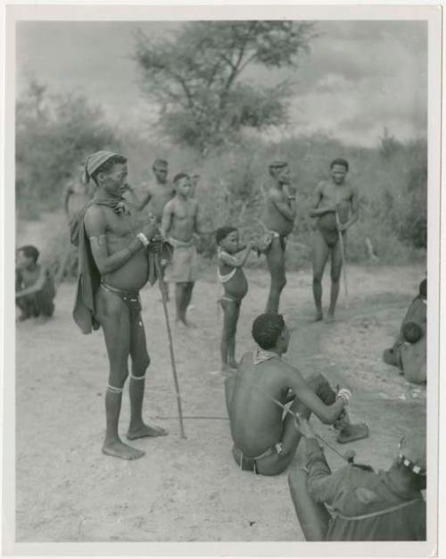 Men preparing to start dancing, from right to left in background: "/Qui Navel", ≠Gao of Band 3, Ngani, and //Ao