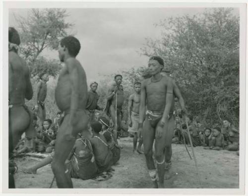 Men dancing in a circle behind the women; shows Ngani, wearing shorts, beginning to go into trance (print is a cropped image)