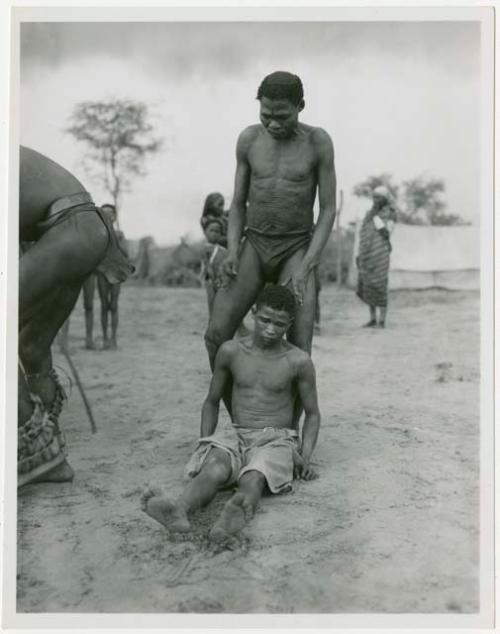 Ngani sitting on the ground, in trance, and "/Qui Navel" standing behind him in partial trance (print is a cropped image)