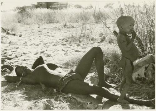 !Gai lying on his back, N!whakwe standing by his feet (print is a cropped image)