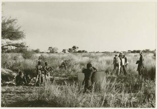 Oukwane, !Gai, /Gaiamakwe, !Ou/ke, and !Oukabe working at a skin; expedition members taking sound sync (print is a cropped image)