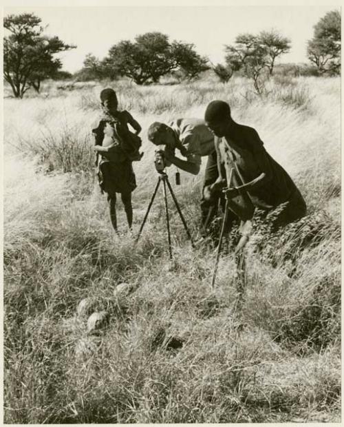 /Twikwe and DaSi!Na standing beside John Marshall while he films (print is a cropped image)