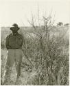 Robert Story standing beside a plant (print is a cropped image)