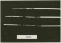 Three arrows against a black background with a ruler for measurement; shows bone point, connecting link, and shaft separated (print is a cropped image)