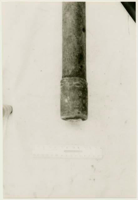 End of a quiver made with bark of a root with a leather end, with a ruler for measurement (print is a cropped image)