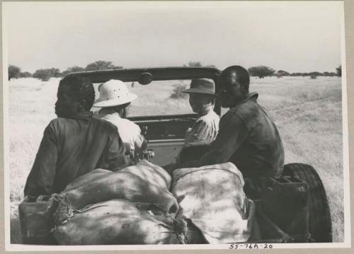 Laurence Marshall sitting behind the wheel in the expedition Jeep, with Lorna Marshall, and other two men present