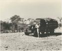 William Donnellan and Kernel Ledimo standing in front of the expedition truck, with huts in the background
