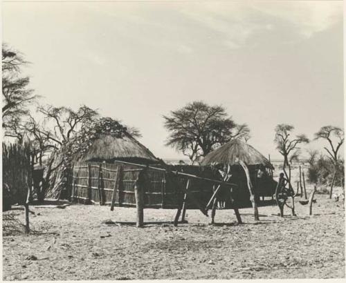 Two huts with a grass fence
