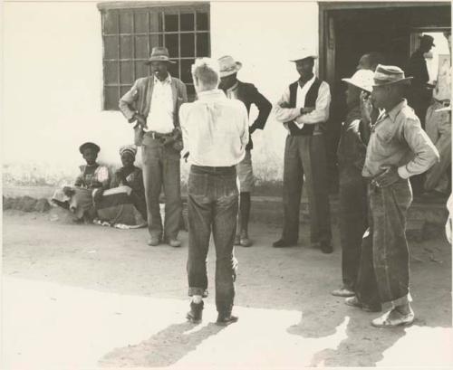 Group of people, including Daniel Blitz and John Marshall, gathered around in front of store at Sehitwe
