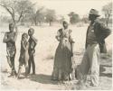 Man in European clothes, a woman in Herero dress, and three boys, full figure standing


