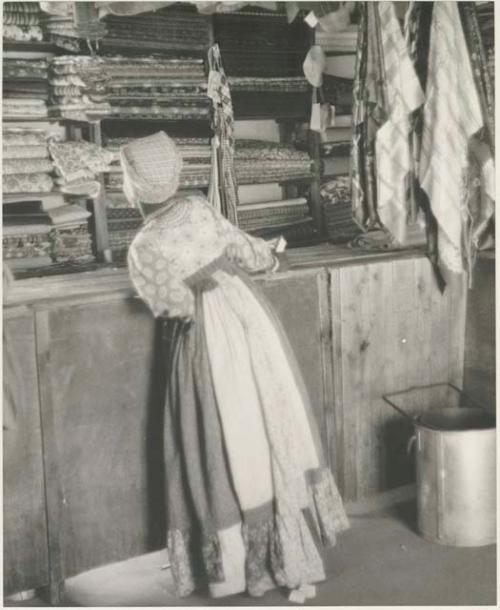 Interior of a trader's store at Sehitwe, with a woman looking at items












