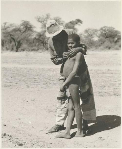 Man standing, wrapping his arms around a boy






