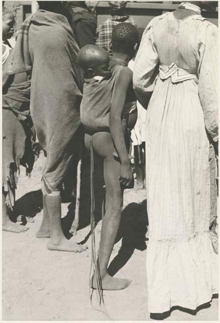 Girl with a baby tied to her back, standing next to a woman