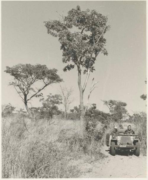 Simon Molamo and William Donnellan sitting in the expedition Jeep on a road