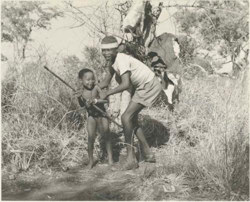 /Gishay ("Old Gau's" son) holding "Little ≠Gao" who has a stick







