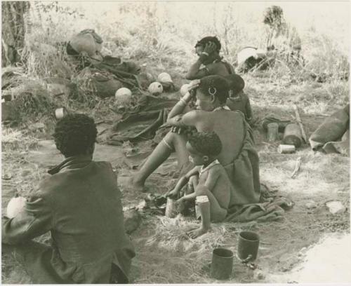 Di!ai, !U, ≠Toma all seated, seen from behind and !Ungka Norna leaning against her mother and Elizabeth Marshall Thomas in the background
































