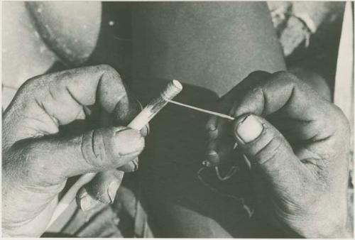 Person's hands scraping arrow shaft with a knife





























