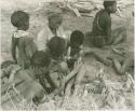Group of women and children including !Ungka and an unidentified woman removing ornaments from /Khoa (/Qui's daughter)












































