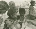 Group of women and children including !Ungka and an unidentified woman removing ornaments from /Khoa (/Qui's daughter)












































