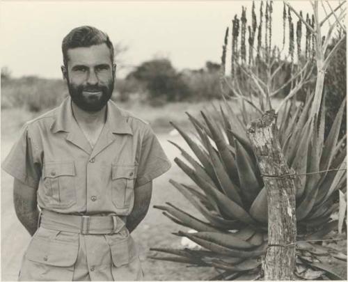 Daniel Blitz with a beard, standing by aloe plant

