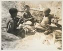 Tsamgao, "Little ≠Gao," and /Gaishay (!U and ≠Toma's son), seated and wearing shoes
