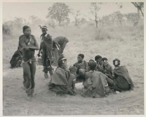 Three men, including /Gunda and ≠Gao, dancing around a group of seated women singing; medicine man leaning over "Gao Medicine" far back behind