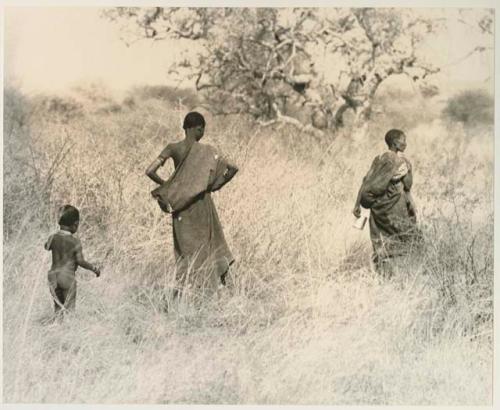 Two women and a child walking in the grass


