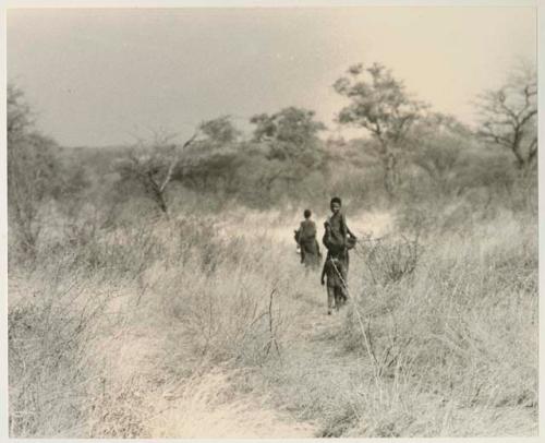 Two women and a child walking in the grass, seen from a distance


