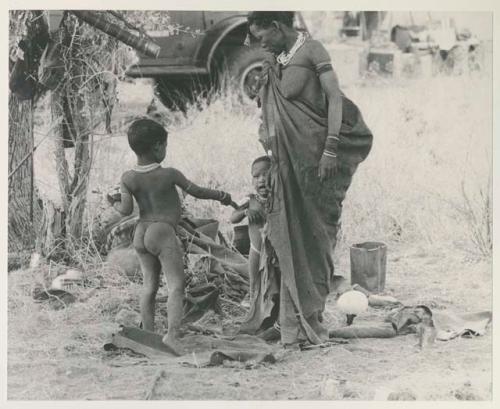 Di!ai (second wife of "Gao Medicine") standing, along with Bau (daughter of //Khuga and "Crooked /Qui") handing Debe (Di!ai's son) the mealies on the spoon









