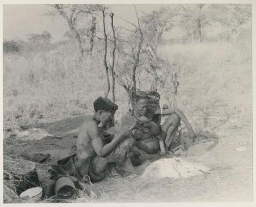 Xuan//a (one of Gau's wives) and her baby, ≠Toma, sitting by their fire























