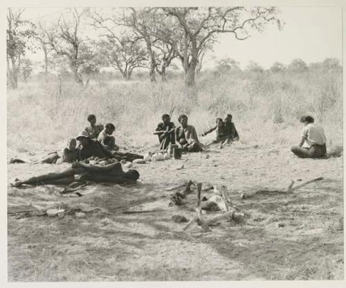 Group sitting including !U, "Old Gau," !Kham holding sticks as crutches, and Elizabeth Marshall Thomas nearby



























