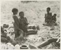 Group sitting including !U smoking a pipe, !Unkga Norna standing next to her, ≠Toma wearing a coat, Be (!Kham's wife) and her youngest child, and an unidentified man


























