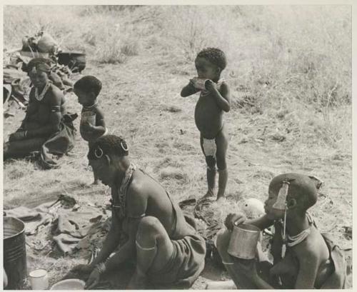 !U seated in the foreground, !Ungka Norna licking a can, an unidentified, visiting girl and Debe holding cans, and Di!ai seated in the background


























