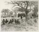 Group under a tree with expedition trucks in the background


























