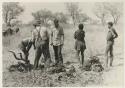 ≠Toma wearing a coat, standing with "Crooked /Qui," Wilhelm Camm and John Marshall next to kudu meat



























