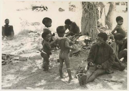 ≠Toma wearing a coat and a group of standing children including Debe ("Gao Medicine's" and Di!ai's son), /Gaishay, !Ungka Norna, Bau to the right, and other unidentified people


























