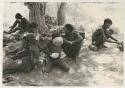 Group of people including two unidentified people to the left, ≠Toma lying down and wearing a coat, !Unkga Norna, an unidentified boy drinking from a bowl, "Crooked /Qui," and /Gaishay ("Gao Medicine's" and /Naoka's son)



























