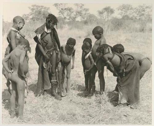 Ju/'hoan youth crowded around a girl wearing a laced boot

























