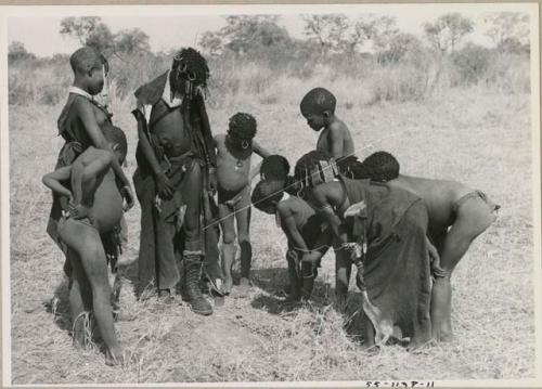 Ju/'hoan youth crowded around a girl wearing a laced boot























