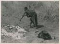 Di!ai preparing to cook a wildebeest head by stirring coals with a stick


























