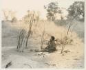 Woman seated by her fire, holding a child
























