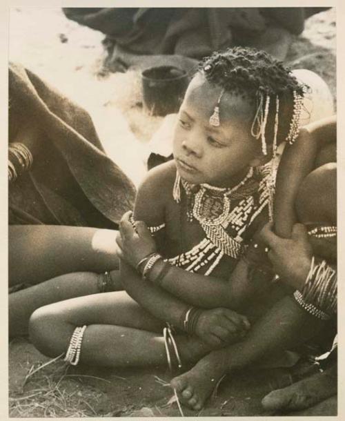 ≠Gisa (daughter of ≠Gao) sitting, wearing beaded ornaments



