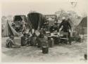 Expedition camp with Ju/'hoansi sitting in the midst; Philip Hameva holding teacups























